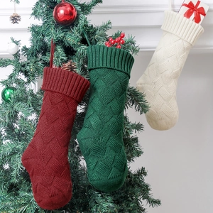 Three knitted Christmas stockings in burgundy, dark green and cream hanging on a tree