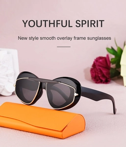 Cat eye sunglasses with black lenses and gold trim next to an orange leather case