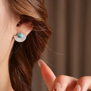 Vintage fan-shaped turquoise stud earrings in silver steel worn by a model