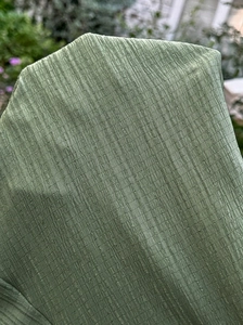 Vue macro détaillée montrant la texture plissée verticale du tissu doux vert pour maternité