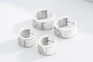 Macro shot of silver polished shell earrings with white enamel inlay in two sizes