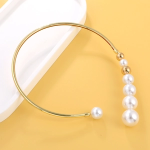 Exaggerated golden metal chain choker with asymmetrical white pearls on yellow background
