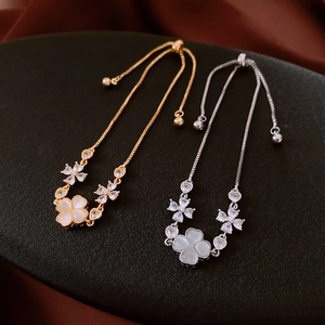 Close-up of gold and silver plated flower slider bracelets with opal four-leaf clover charms