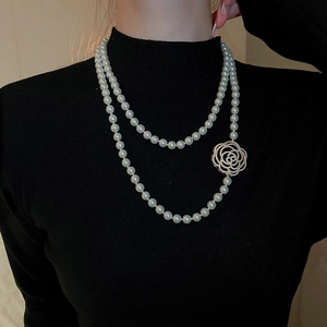 Gros plan d'un collier de perles avec fermoir décoratif en forme de camélia serti
