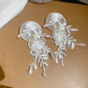 Détails de boucles d'oreilles en dentelle blanche avec accents floraux en résine