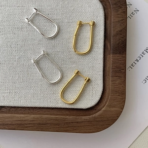Detailed view of U-shaped sterling silver hoop earrings in polished gold and silver finishes