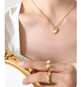 Close-up of gold heart necklace with cat's eye stone and elegant pearl open rings