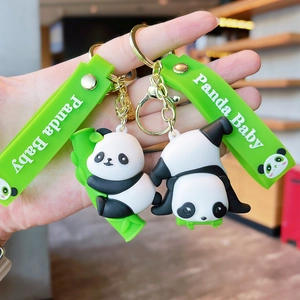 Close-up of cute cartoon panda keychain featuring a green wristband and bamboo accessory