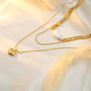 Detail of 18k gold heart pendant necklace featuring baroque pearl on luxury satin