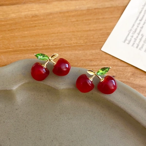Detailed shot of cherry earrings with red resin fruits and green crystal leaves
