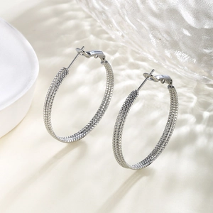 Macro detail of silver hoop earrings featuring triple row textured chain link design