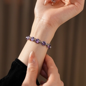 Macro shot of a silver bracelet featuring purple round zircon stones on a model's wrist