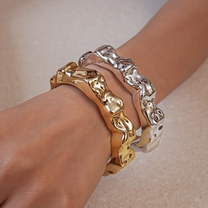 Macro detail of irregular lava texture gold and silver open bangles with liquid metal finish