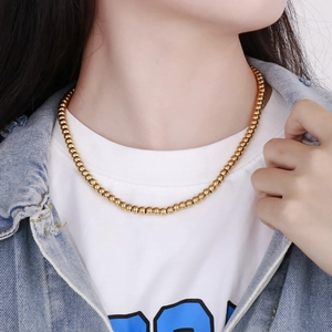 Gros plan d'un collier de perles en acier inoxydable plaqué or 18 carats sur un mannequin