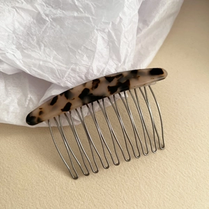 Detailed view of tortoise shell acetate hair comb with sturdy metal teeth on white paper