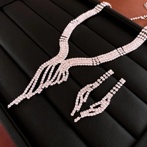 Macro shot of silver tassel necklace and earrings set with sparkling rhinestones on black