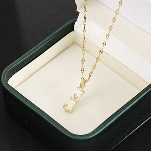Macro detail of golden bamboo pendant with white inlay and crystals in green jewelry box