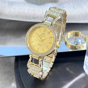 Gros plan d'une montre à quartz dorée avec lunette en cristal et cadran rayonnant