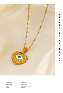 Detail of gold heart necklace with blue evil eye pendant on textured fabric