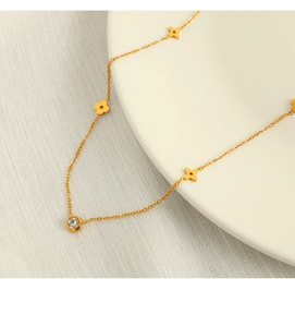 Detail of gold star necklace with floral charms and diamond pendant on white ceramic tray