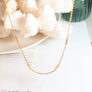 Elegant minimalist gold chain necklace with polished rectangular bar links on white coral