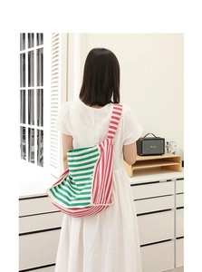 Dettaglio della borsa tote in maglia a righe verdi e bianche indossata da modella