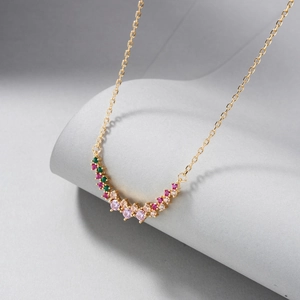 Close-up of curved gold necklace with vibrant multi-colored cubic zirconia gemstones