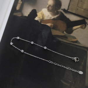 Detail of silver stainless steel bracelet featuring five round white zircons on a fine chain