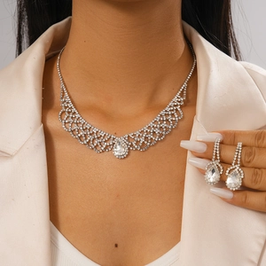 Close-up of silver mesh necklace and teardrop rhinestone earrings worn by a model