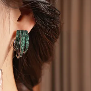 Green zircon multi-layered C-shaped earrings in dark metal finish worn by a model