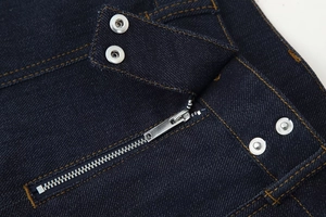Détail du tissu denim bleu foncé avec fermetures éclair en métal et boutons-pression