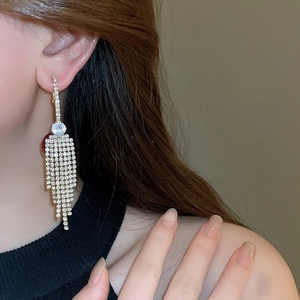 Detailed view of long gold tassel earrings with shimmering cubic zirconia on a model