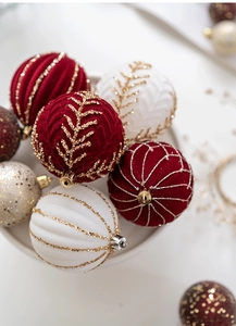 Close-up of velvet red and champagne gold Christmas balls with glitter patterns on a tray