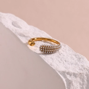 Detailed close-up of a gold open ring with micro-set pearls on a stone base