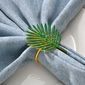 Elegant gold metal napkin ring featuring a vibrant green enamel palm leaf design