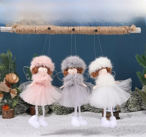 Close-up of three plush Christmas angel dolls with gauze skirts on a wooden branch
