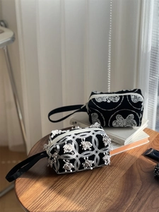 Detail view of black canvas handbags featuring traditional embroidery and elegant tassels