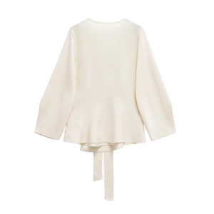 Close-up of cream knit sweater showing ruffled hem and matching waist tie detail