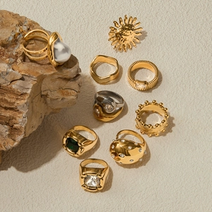 Detailed arrangement of gold pearl and zircon titanium steel rings on a stone surface