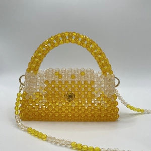 Detail of yellow and clear beaded handbag with gold-tone hooks and woven texture