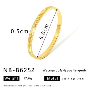Detailed macro view of gold-plated stainless steel bangle with diamond accents and hinge