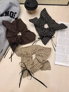 Three plaid pattern hair scrunchies with black ribbons styled with coffee and newspapers