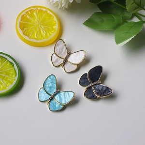 Detailed view of three butterfly brooches with pearls and crystals on white background