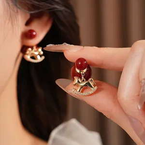 Elegant gold-plated rocking horse earrings with red beads and sparkling cubic zirconia