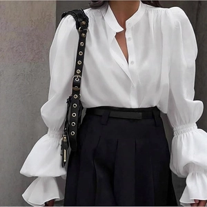 Close-up of elegant white blouse featuring ruffled lantern sleeves and button detail