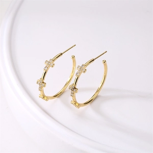 Close-up of gold-plated cross C-shaped earrings inlaid with sparkling clear zircons