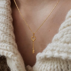 Vintage gold key pendant necklace for women worn on a cozy beige knit sweater