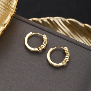 Detail of 18K gold plated huggie earrings featuring four claw-set cubic zirconia stones