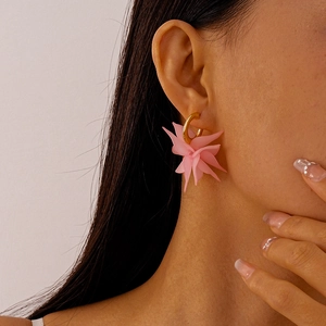 Close-up of pink layered acrylic flower earrings with gold C-shaped metal hoops