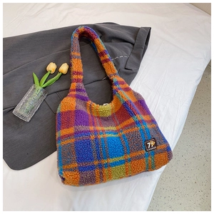 Detail of multi-color plaid sherpa tote bag with fashion tag on a cozy fabric background